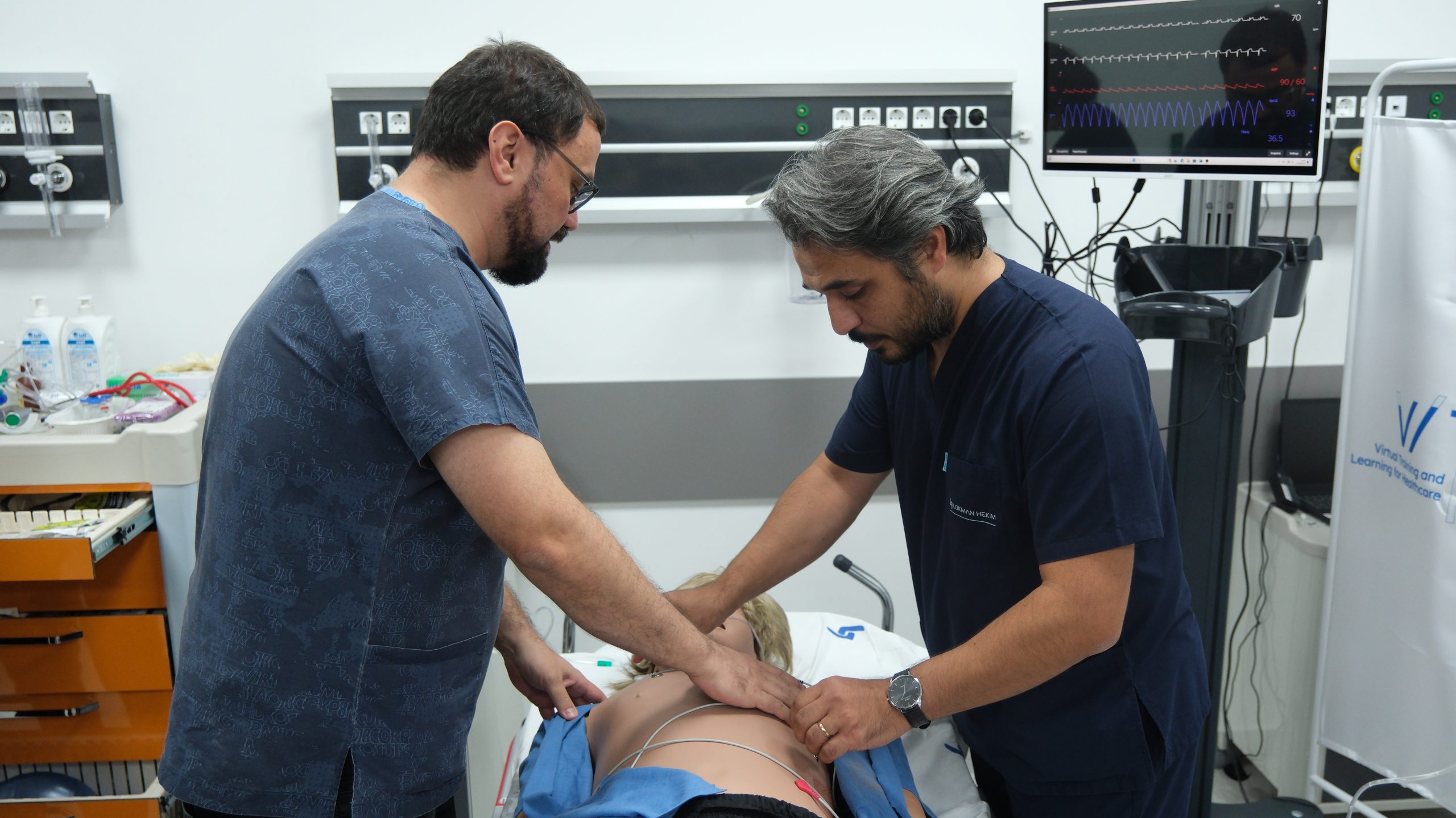 Sağlıkta simülasyon eğitim ortamında gerçekleştirilen uygulamalı sağlık eğitimi çalışması. | Hands-on training session in a healthcare simulation environment with students practicing clinical skills.
